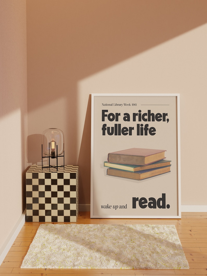 May include: A white framed poster with the text "National Library Week 1961" and the message "For a richer, fuller life wake up and read." The poster is on a wall with a checkered black and white side table and a glass lamp with a black base.
