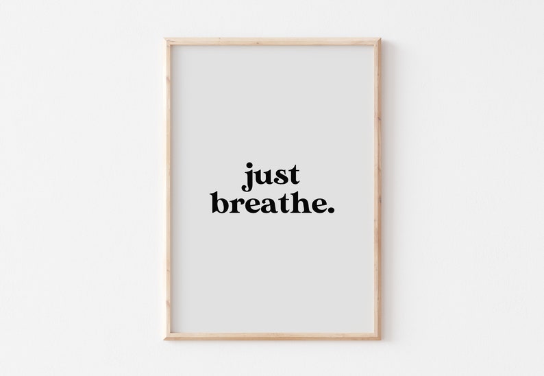 May include: A framed print with a white background and black text that reads "just breathe."