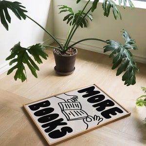 Peut inclure: Une impression encadr&eacute;e avec une illustration en noir et blanc de deux mains tenant un livre ouvert. Le texte "MORE BOOKS" est &eacute;crit en grandes lettres grasses.