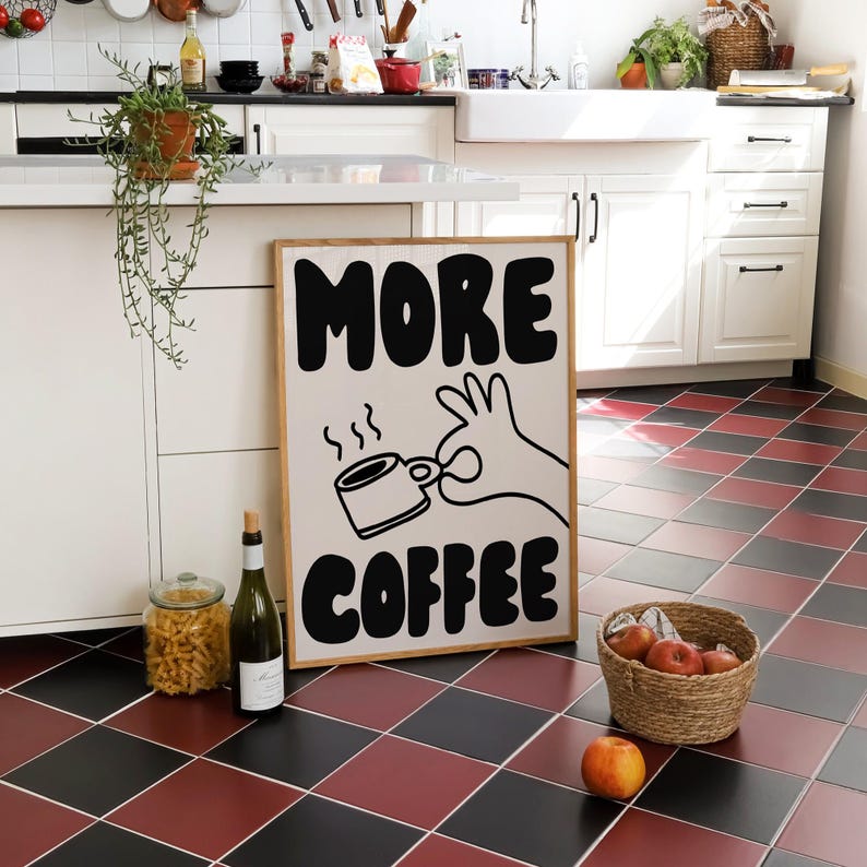May include: A white sign with black text and a cartoon hand holding a coffee cup. The sign reads "MORE COFFEE".