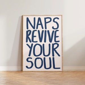 May include: A framed poster with the text "NAPS REVIVE YOUR SOUL" in blue paint on a light pink background.