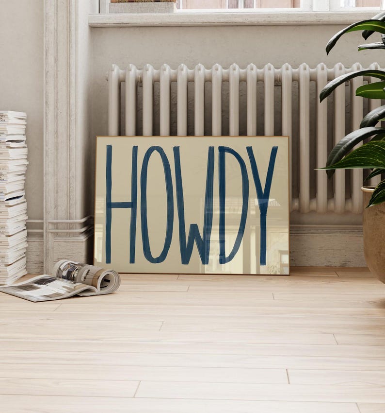 Puede incluir: Una impresi&oacute;n enmarcada con la palabra "HOWDY" escrita en una fuente grande, negrita y azul sobre un fondo beige.