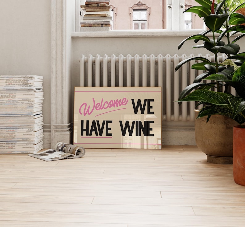 May include: A beige sign with the text "Welcome We Have Wine" in black lettering. The word "Welcome" is written in pink cursive.