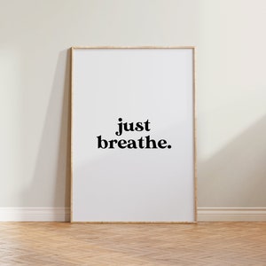 May include: A framed print with the text "just breathe." in black bold font on a white background.