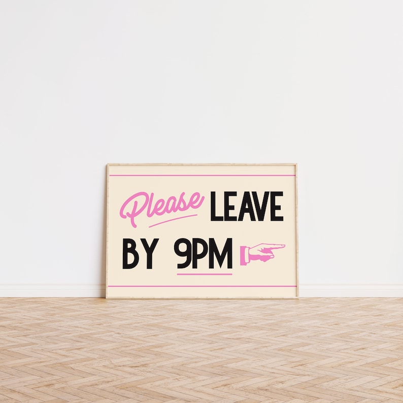 May include: A framed sign with the text "Please LEAVE BY 9PM" in pink and black. The sign has a cream-colored background and a pink hand pointing to the right. The frame is a light wood color.
