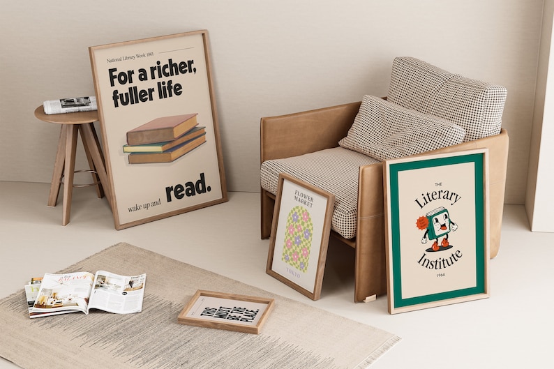 May include: A living room interior with a beige armchair, a rug, and a side table with a magazine on top. There are four framed posters on the wall and on the floor. One poster says "For a richer, fuller life, wake up and read." Another poster says "Flower Market." The third poster says "The Literary Institute 1944." The fourth poster says "You must be the place".