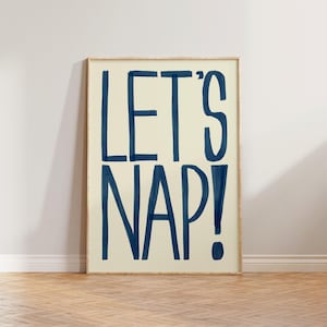 May include: A white poster with a blue inscription that reads "LET'S NAP!" in a bold, handwritten font.
