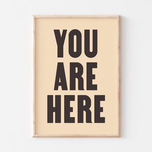 Peut inclure: Une impression encadr&eacute;e avec un fond beige clair et un texte noir qui dit "YOU ARE HERE".
