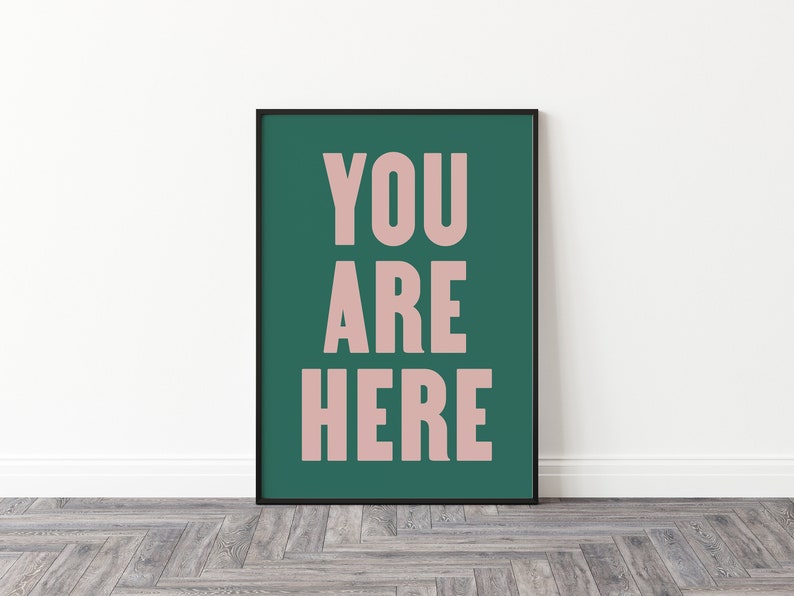 Peut inclure: Une impression encadr&eacute;e avec un fond vert sarcelle et les mots "YOU ARE HERE" en rose clair.
