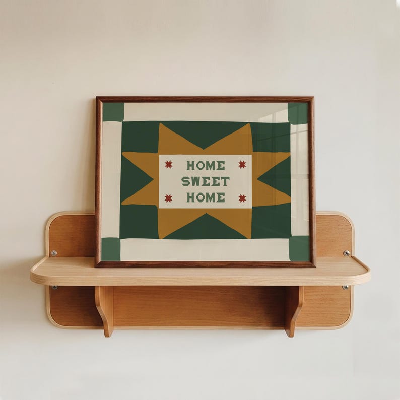 Puede incluir: Una impresi&oacute;n rectangular enmarcada con un patr&oacute;n de estrellas en verde oscuro y amarillo mostaza sobre un fondo crema. El centro contiene el texto "HOME SWEET HOME" en letras may&uacute;sculas verde oscuro, flanqueado por cuatro estrellas rojas.