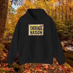 Könnte beinhalten: Schwarzer Kapuzenpullover mit einem gelben und roten Grafikdruck eines Schildes mit der Aufschrift "Cherokee Nation".