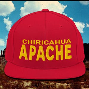 May include: A red and yellow baseball cap with the text "Chiricahua Apache" embroidered on the front.