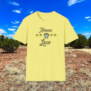 May include: A yellow t-shirt with the text "Apache Land" in a vintage font. There are five yellow stars above the text and a Native American headdress graphic in the center.