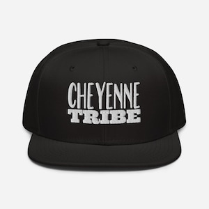 May include: A black flat-brimmed baseball cap with the white embroidered text "CHEYENNE TRIBE" across the front. The cap has a structured fit and a flat visor. The hat is a classic accessory.