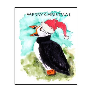 May include: Watercolor Christmas card featuring a puffin wearing a Santa hat. The puffin has black and white feathers, an orange beak, and orange feet. The words "Merry Christmas" are written above the puffin in black text. The background has green and blue watercolor washes.