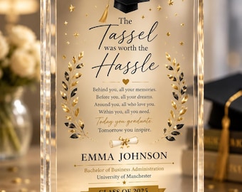 May include: A rectangular clear acrylic plaque featuring a black graduation cap icon, gold laurel branches, and the text: The Tassel was worth the Hassle, Emma Johnson, Bachelor of Business Administration, University of Manchester, Class of 2025.