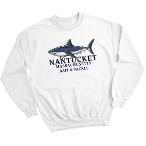 May include: A white crewneck sweatshirt featuring a dark blue graphic of a shark swimming above the text NANTUCKET MASSACHUSETTS BAIT & TACKLE. The long-sleeved garment has a ribbed collar, cuffs, and hem, displaying a clean and simple design.