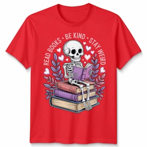 May include: Red t-shirt with a graphic of a skeleton reading a book atop a pile of books. The design includes the text "Read Books, Be Kind, Stay Weird" with heart and leaf accents. A unique graphic tee.