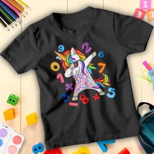 May include: Black t-shirt with a unicorn design dabbing, featuring a rainbow mane and horn. The unicorn is covered in numbers and math symbols. Numbers 1 to 9 are scattered around the unicorn.