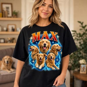 May include: A black t-shirt featuring a graphic print of four golden retriever dogs arranged around the word MAX in bold red letters. The design includes bright blue lightning bolts and small white stars surrounding the dogs on a dark background.