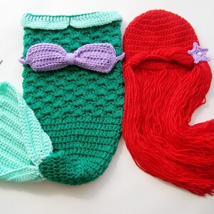 May include: A crocheted mermaid tail costume in green and light blue with a purple bow. A red crocheted hat with a long red yarn tail and a purple star.