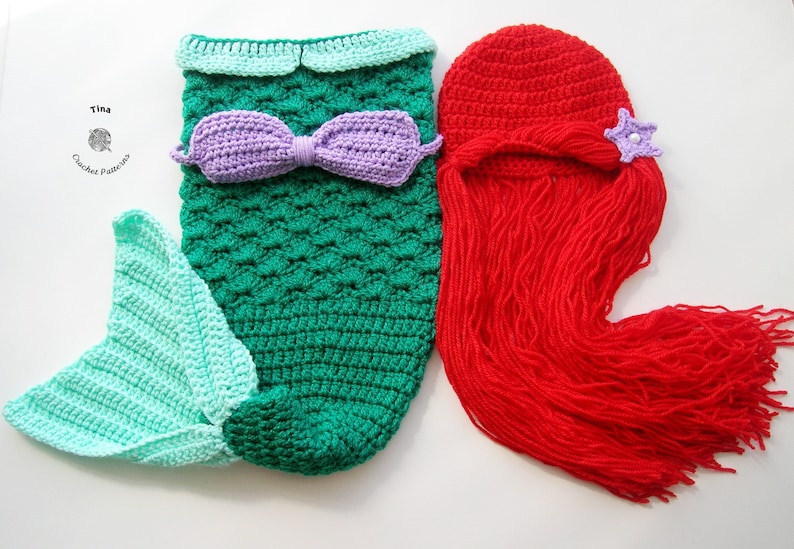 May include: A crocheted mermaid tail costume in green and light blue with a purple bow. A red crocheted hat with a long red yarn tail and a purple star.