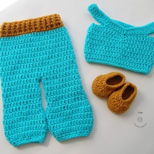 Puede incluir: Un conjunto de bebé de ganchillo en color turquesa y marrón. El conjunto incluye pantalones, una parte superior y botines.