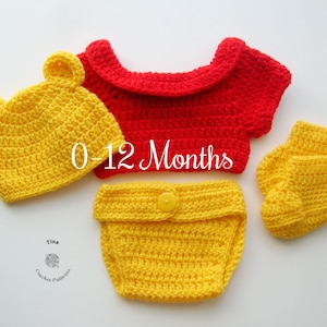 May include: A crocheted baby outfit in red and yellow. The outfit includes a hat, a shirt, a diaper cover, and booties. The outfit is sized for 0-12 months.