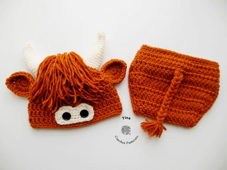 May include: A handmade crochet Highland cow costume set, featuring a rust-colored hat with white horns, ears, and a shaggy mane, along with matching shorts with a braided tail. The set is designed for a baby.