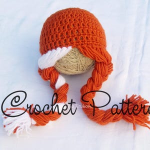 May include: Orange and white crocheted hat with two long braids. The hat is on a beige ball of yarn. The text "Crochet Pattern" is visible in the image.