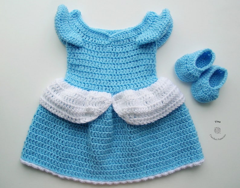 Peut inclure: Une robe de b&eacute;b&eacute; en crochet bleu clair avec des bordures blanches et des chaussures de b&eacute;b&eacute; en crochet bleu clair assorties. La robe a une jupe &agrave; volants et une ouverture dans le dos.