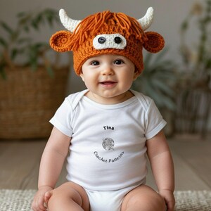 May include: A baby wearing a handmade crochet hat shaped like a Highland cow, with orange yarn and white horns. The baby is also wearing a white onesie with the name "Tina" and the text "Crochet Patterns".