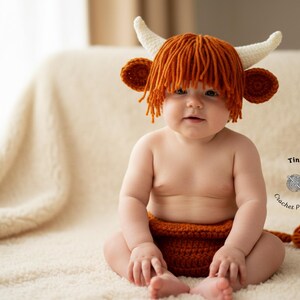 May include: A baby wearing a crocheted Highland cow costume, including a hat with horns and orange yarn hair, and a matching diaper cover. The baby is sitting on a cream-colored blanket.