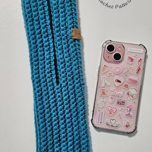 Può includere: Una custodia per telefono turchese, lavorata a mano all'uncinetto, con un'apertura rettangolare. Una piccola etichetta rettangolare è attaccata alla custodia. Una custodia per telefono rosa con vari adesivi è accanto alla custodia. Il testo "Tina Crochet Patterns" è sullo sfondo.