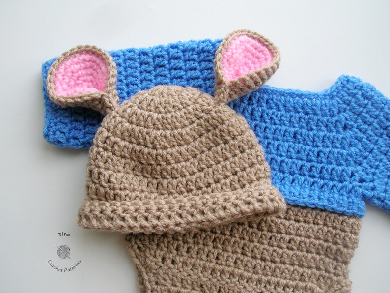 May include: A brown crocheted hat with pink ears and a blue crocheted sweater.