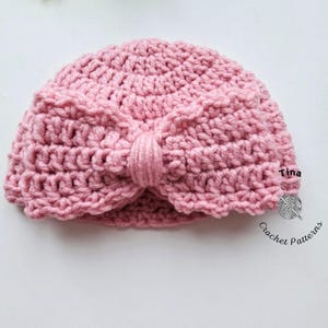 May include: A light pink crochet turban-style hat with a knotted bow detail. The hat is handmade with a textured stitch and features the text "Tina" and "Crochet Patterns".