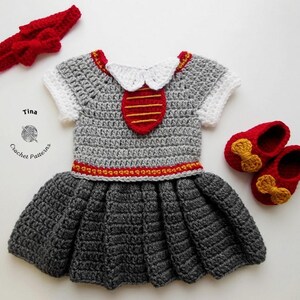 May include: A gray crocheted dress with a red and gold trim, a white crocheted collar, and a red and gold crocheted tie. The dress is paired with a red crocheted headband and red crocheted shoes with gold bows.