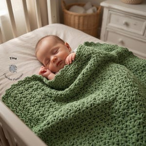 May include: A sleeping baby is nestled in a crib, covered by a soft, green crocheted blanket. The blanket features a textured starburst pattern. The image is a close-up, highlighting the baby and the blanket's details. The blanket is a soft, sage green color.