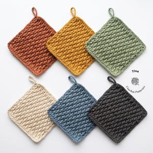 Può includere: Una collezione di sei presine quadrate fatte a mano all'uncinetto, nei colori ruggine, giallo senape, verde salvia, crema, blu polveroso e grigio antracite. Ogni presina presenta un motivo a punto strutturato e un piccolo anello per appenderla.