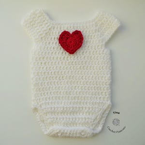 Op de afbeelding: Witte gehaakte baby romper met een rode hart-applicatie. Tina Crochet Patterns.