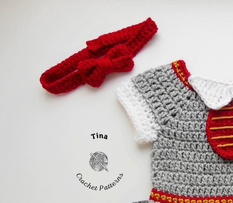 May include: A gray crocheted baby outfit with red and gold accents. The outfit has a white collar and a red bow headband.
