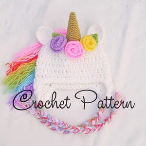 Peut inclure: Chapeau de licorne en crochet blanc avec une crini&egrave;re arc-en-ciel et une corne dor&eacute;e. Le chapeau est d&eacute;cor&eacute; de fleurs violettes, jaunes et roses. Mod&egrave;le de crochet.