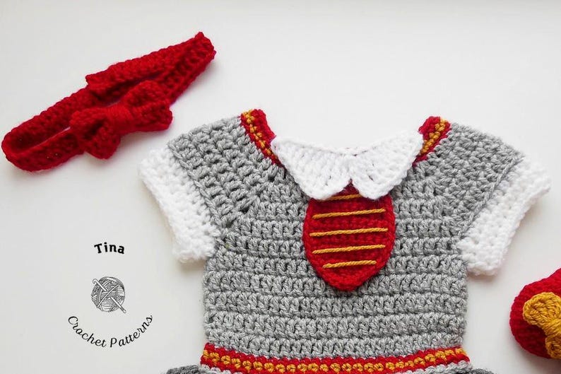 May include: A gray crocheted baby outfit with a red and yellow trim. The outfit has a white crocheted collar and a red crocheted tie with yellow stripes. The outfit is accompanied by a red crocheted headband with a bow.