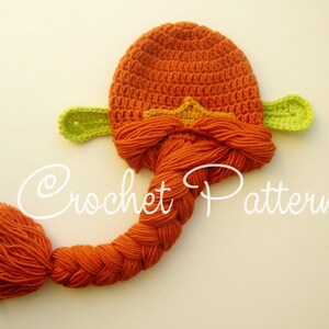 May include: Orange crochet hat with a long braided tail and green leaf-shaped ears. The hat has a yellow star on the top.
