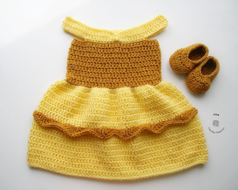 K&ouml;nnte beinhalten: Ein gelbes und braunes geh&auml;keltes Babykleid mit einem R&uuml;schenrock und passenden geh&auml;kelten Schuhen. Das Kleid hat einen einfachen, schulterfreien Ausschnitt.