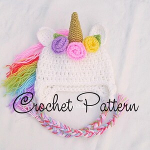 Peut inclure: Chapeau de licorne en crochet blanc avec une crini&egrave;re arc-en-ciel et une corne dor&eacute;e. Le chapeau est d&eacute;cor&eacute; de fleurs violettes, jaunes et roses. Mod&egrave;le de crochet.