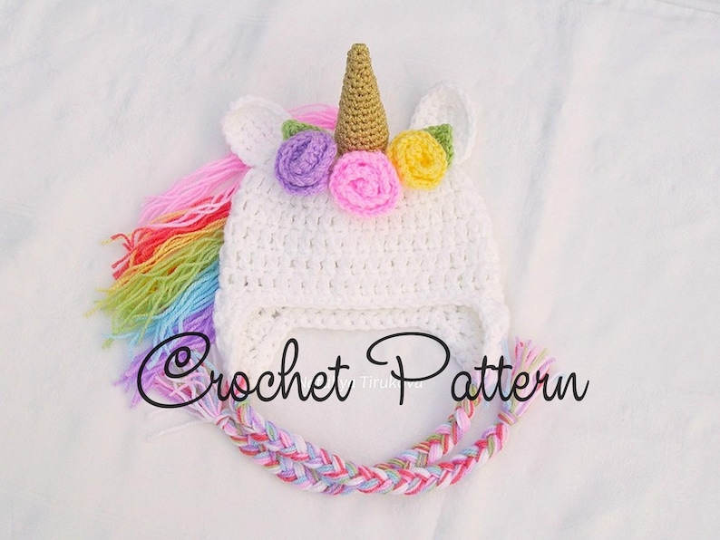 Peut inclure: Chapeau de licorne en crochet blanc avec une crini&egrave;re arc-en-ciel et une corne dor&eacute;e. Le chapeau est d&eacute;cor&eacute; de fleurs violettes, jaunes et roses. Mod&egrave;le de crochet.