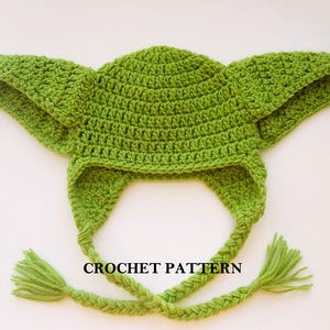 Puede incluir: Sombrero de crochet verde con largas orejeras y una correa de barbilla trenzada. El sombrero tiene la forma del personaje Yoda de Star Wars. El texto "CROCHET PATTERN" es visible en el sombrero.