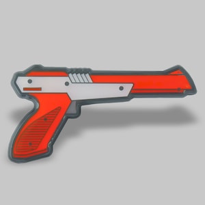 May include: A red and white plastic toy gun, resembling a classic video game weapon.