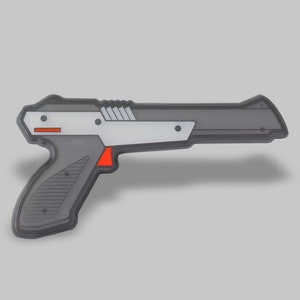 May include: A gray and silver plastic toy gun with a red trigger. The gun is a replica of a classic video game weapon.